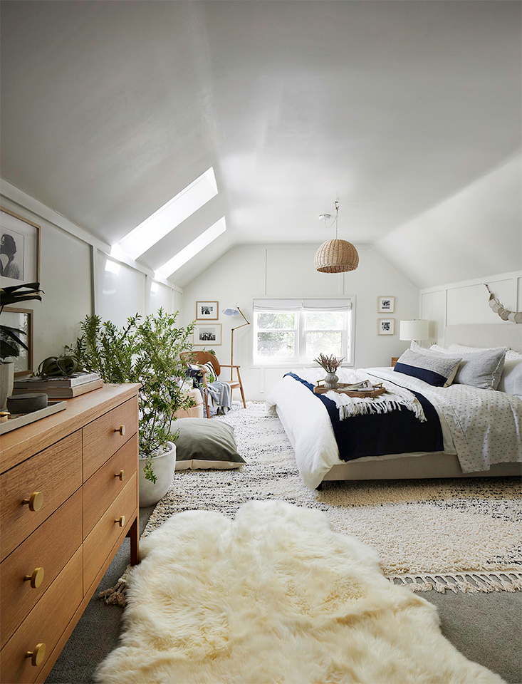 Cozy bedroom with soft, neutral tones and two skylights filling the room with natural light, creating a warm and serene atmosphere.